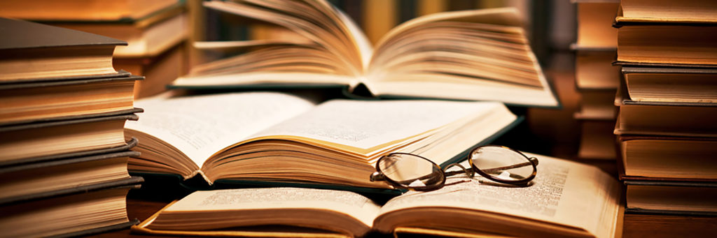 photo of a stack of books with a pair of reading glasses on top