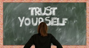 photo of woman facing a black board with the words "trust yourself"