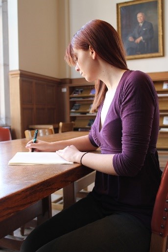 photo of a woman sitting at a desk and writing